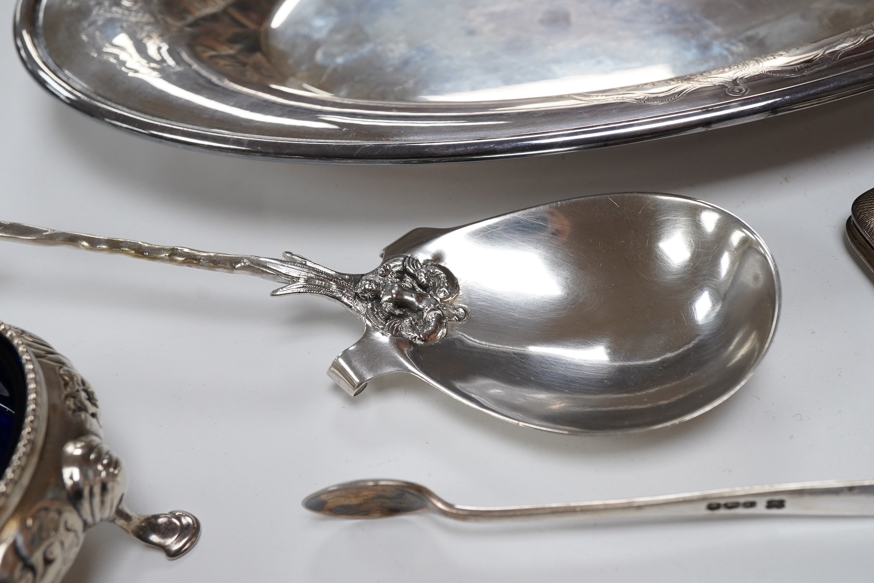 A Victorian silver bun salt, London, 1860, a later silver cigarette case, a silver napkin ring and pair of silver sugar tongs, together with a continental white metal serving spoon and a silver plated oval tray.